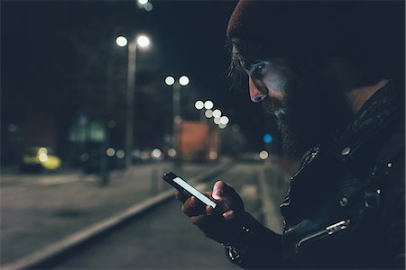 real people urban - Young male hipster on city street looking at smartphone at night Stock Photo - Premium Royalty-Free, Code: 649-08969983