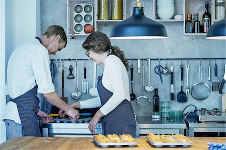 Two chefs in kitchen, removing freshly baked canapes from baking tray Stock Photo - Premium Royalty-Free, Code: 649-08987882