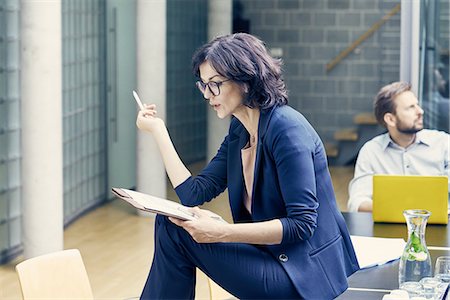 simsearch:614-09078768,k - Businesswoman sitting looking at paperwork on boardroom table Foto de stock - Sin royalties Premium, Código: 649-08988196