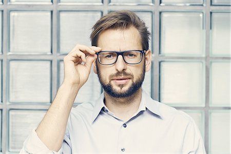 simsearch:614-08990534,k - Portrait of businessman holding eyeglasses by office glass wall Foto de stock - Sin royalties Premium, Código: 649-08988199