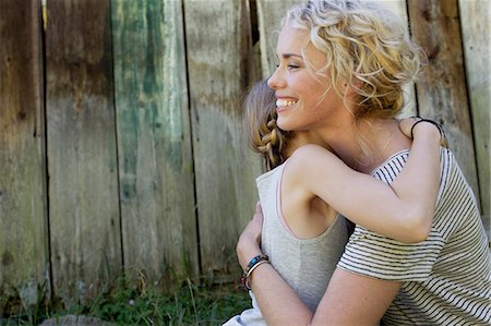 Mother and daughter hugging, wooden fence in background Stock Photo - Premium Royalty-Free, Code: 649-08988364
