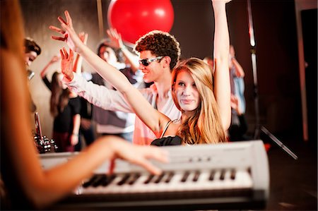 people dancing in night club with arms in air - Young woman playing keyboard with people dancing Stock Photo - Premium Royalty-Free, Code: 649-09004358