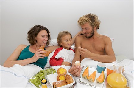 feeding grapes to men pictures - young familiy having breakfast in bed Stock Photo - Premium Royalty-Free, Code: 649-09002537