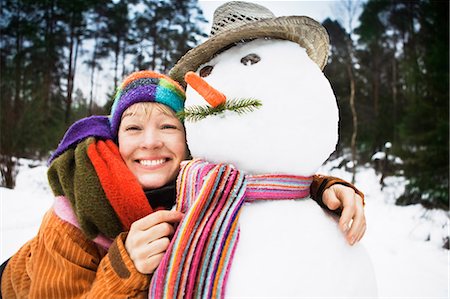 Smiling woman hugging snowman Stock Photo - Premium Royalty-Free, Code: 649-09003435