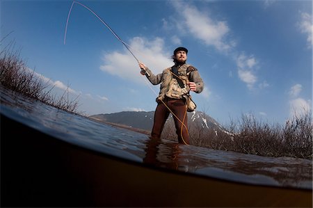 pesca con la mosca - Low angle view of man fishing in lake Fotografie stock - Premium Royalty-Free, Codice: 649-09003447