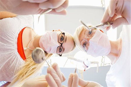 female dentist looking at camera - Dentists working on patients teeth Stock Photo - Premium Royalty-Free, Code: 649-09003466