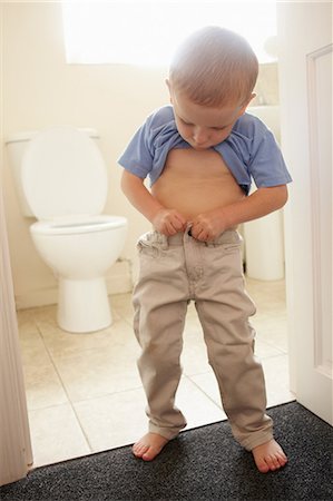 Boy buttoning his pants in bathroom Fotografie stock - Premium Royalty-Free, Codice: 649-09003837