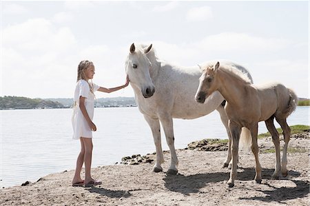 simsearch:649-09003874,k - Girl petting horses on sandy beach Foto de stock - Royalty Free Premium, Número: 649-09003858