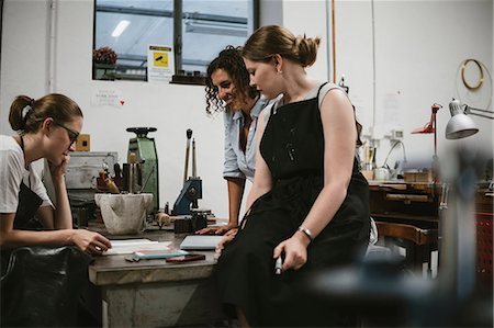 Three female jewellers looking at sketchpad at workbench meeting Photographie de stock - Premium Libres de Droits, Code: 649-09016598