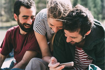 simsearch:649-09111243,k - Three young adult friends looking and laughing at smartphone, Lombardy, Italy Photographie de stock - Premium Libres de Droits, Code: 649-09016755