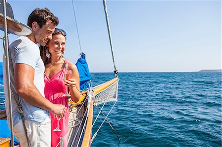 simsearch:649-07521119,k - Couple standing on boat, on water, holding champagne flutes, looking at view Photographie de stock - Premium Libres de Droits, Code: 649-09017126