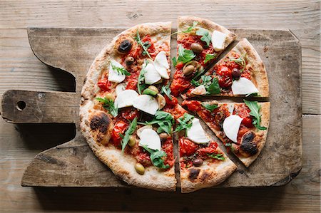 rustic cheese - Sliced pizza on chopping board, overhead view Stock Photo - Premium Royalty-Free, Code: 649-09025478