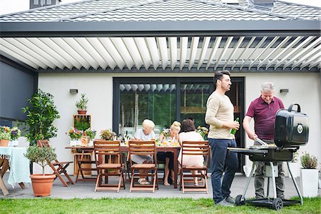 simsearch:649-09025497,k - Two men barbecuing on patio at family lunch Photographie de stock - Premium Libres de Droits, Code: 649-09025491