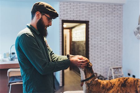 simsearch:649-08840788,k - Man in flat cap petting dog in apartment Foto de stock - Sin royalties Premium, Código: 649-09025527