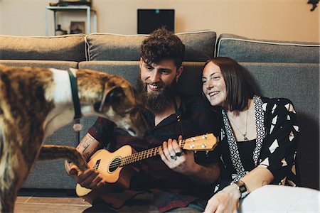 Couple sitting on apartment floor holding dog's paw Stock Photo - Premium Royalty-Free, Code: 649-09025534