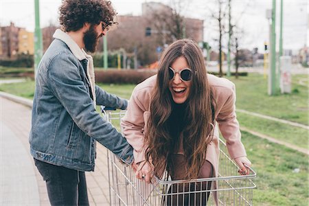simsearch:649-09025622,k - Young couple outdoors, man pushing woman along in shopping trolley Stock Photo - Premium Royalty-Free, Code: 649-09025614