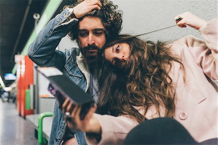 simsearch:649-09025622,k - Young couple sitting in train station, looking at smartphone, worried expressions Stock Photo - Premium Royalty-Free, Code: 649-09025615