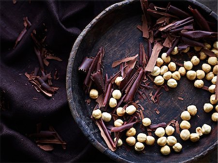 Chocolate shavings and hazelnuts in bowl, overhead view Stock Photo - Premium Royalty-Free, Code: 649-09025789