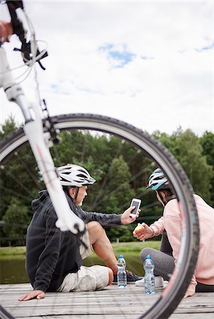 Mature couple relaxing on jetty beside lake, bicycles behind them Stock Photo - Premium Royalty-Free, Code: 649-09025924