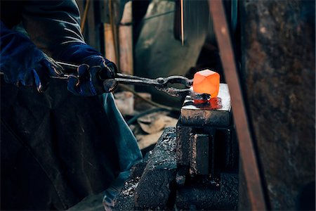 simsearch:649-09026034,k - Gloved hands of blacksmith using tongs for red hot metal Photographie de stock - Premium Libres de Droits, Code: 649-09026025