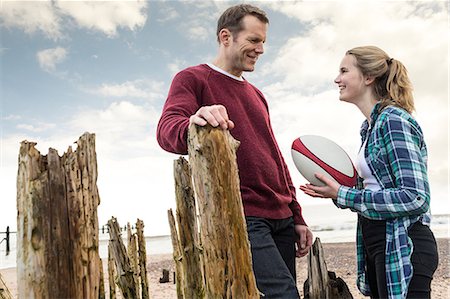 parent talking to their 16 year old - Father and daughter at beach, talking, daughter holding rugby ball Stock Photo - Premium Royalty-Free, Code: 649-09026107