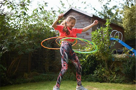 simsearch:649-09026125,k - Teenage girl hula hooping with four plastic hoops in garden Foto de stock - Sin royalties Premium, Código: 649-09026120