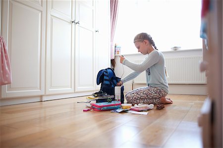 simsearch:649-09026125,k - Girl kneeling on floor packing school bag Foto de stock - Sin royalties Premium, Código: 649-09026134