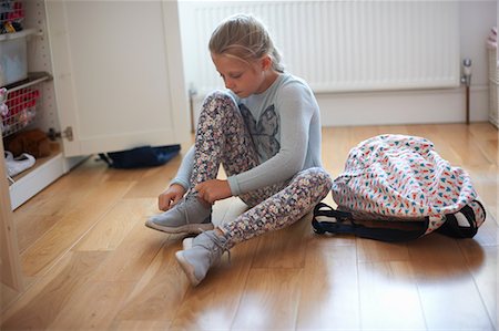 Girl sitting on bedroom floor tying booty laces Photographie de stock - Premium Libres de Droits, Code: 649-09026136