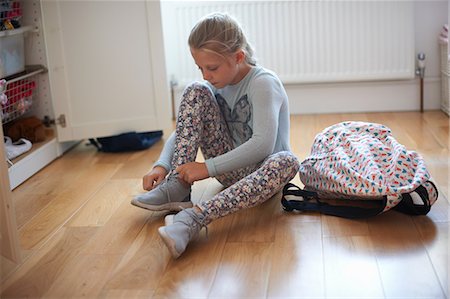 Girl sitting on bedroom floor tying booty laces Foto de stock - Sin royalties Premium, Código: 649-09026136