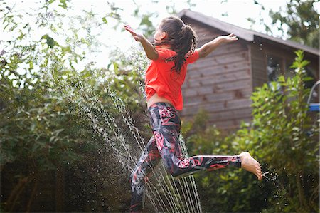 simsearch:649-09026145,k - Girl jumping over garden sprinkler Photographie de stock - Premium Libres de Droits, Code: 649-09026147