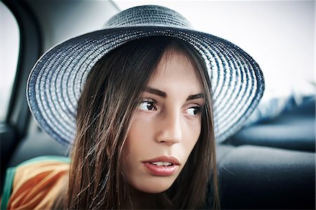 Young woman in sunhat looking sideways from car backseat Stock Photo - Premium Royalty-Free, Code: 649-09026185