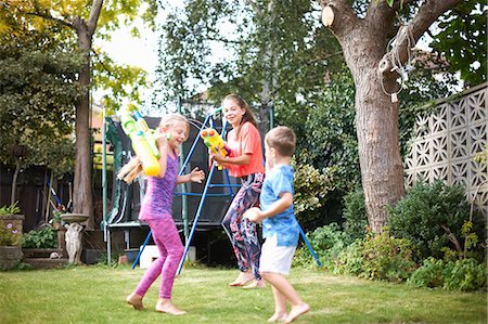 Boy and his sisters having water gun fight in garden Stock Photo - Premium Royalty-Free, Code: 649-09026194