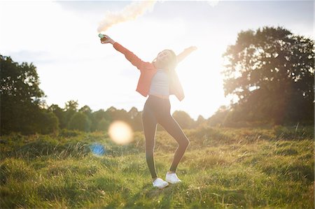 simsearch:649-08117852,k - Young woman letting off smoke flare in sunlit field Photographie de stock - Premium Libres de Droits, Code: 649-09026291