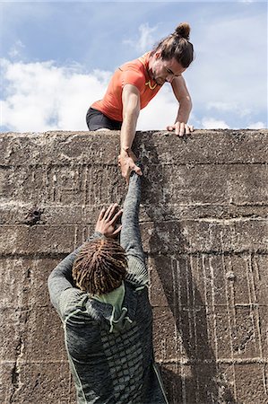 pulling shorts - Young male free climber at top of sea wall helping friend climb up Stock Photo - Premium Royalty-Free, Code: 649-09035637
