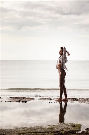 simsearch:6102-07769358,k - Young female runner at water's edge on beach stretching arms Stock Photo - Premium Royalty-Free, Code: 649-09035647