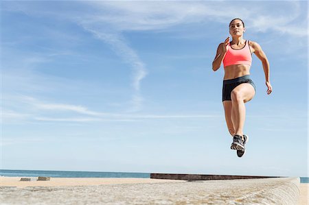 simsearch:614-06336437,k - Young woman running along sea wall, mid air Stock Photo - Premium Royalty-Free, Code: 649-09035679