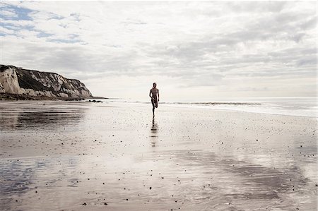 simsearch:6122-07698282,k - Young woman running along beach Photographie de stock - Premium Libres de Droits, Code: 649-09035686