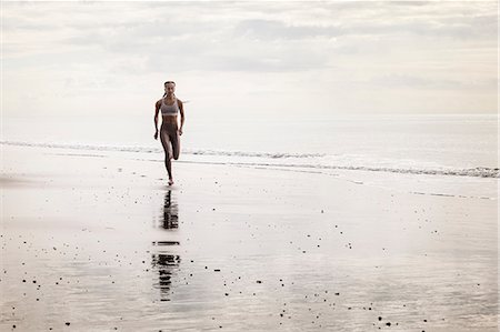 simsearch:6122-07698282,k - Young woman running along beach Photographie de stock - Premium Libres de Droits, Code: 649-09035691
