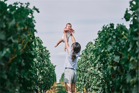 Woman holding up baby daughter in vineyard, Bergerac, Aquitaine, France Photographie de stock - Premium Libres de Droits, Code: 649-09036034