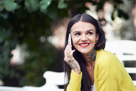 person smartphone tattoo - Young woman sitting outdoors, using smartphone, smiling, tattoos on hand and neck Stock Photo - Premium Royalty-Free, Code: 649-09036131