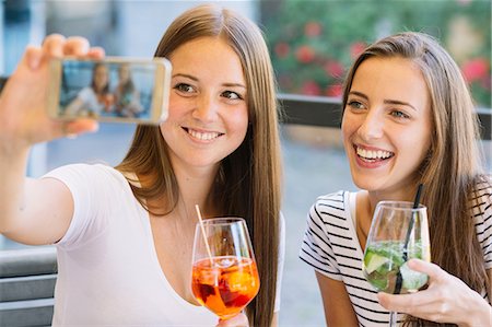 simsearch:649-08824511,k - Two young female friends taking smartphone selfie at sidewalk cafe Stock Photo - Premium Royalty-Free, Code: 649-09036305
