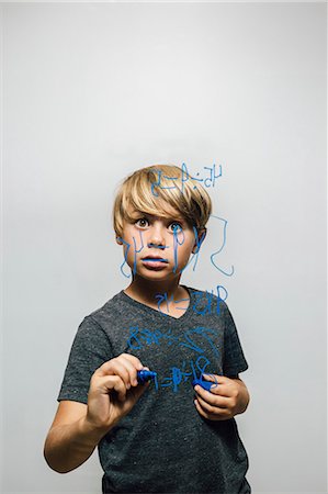 Boy holding blue marker pen staring at equation on glass wall Photographie de stock - Premium Libres de Droits, Code: 649-09036357