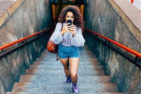 souterrain - Woman coming up stairs and using mobile phone, Milan, Italy Photographie de stock - Premium Libres de Droits, Code: 649-09061277