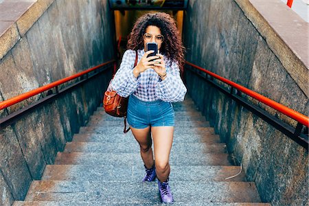 Woman coming up stairs and using mobile phone, Milan, Italy Photographie de stock - Premium Libres de Droits, Code: 649-09061277