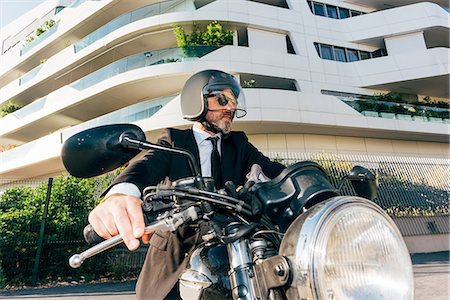 Portrait of mature businessman outdoors, sitting on motorcycle, wearing motorcycle helmet Stock Photo - Premium Royalty-Free, Code: 649-09061335