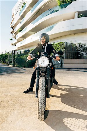 Portrait of mature businessman outdoors, sitting on motorcycle, wearing motorcycle helmet Stock Photo - Premium Royalty-Free, Code: 649-09061336