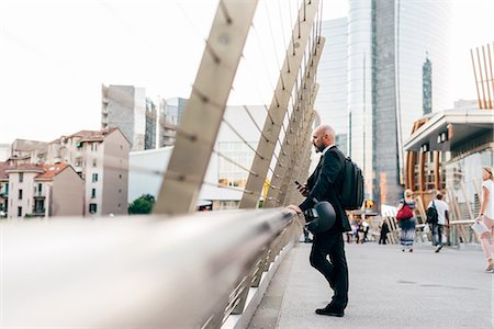 simsearch:649-09061360,k - Mature businessman standing on bridge, looking at view, holding smartphone Photographie de stock - Premium Libres de Droits, Code: 649-09061347