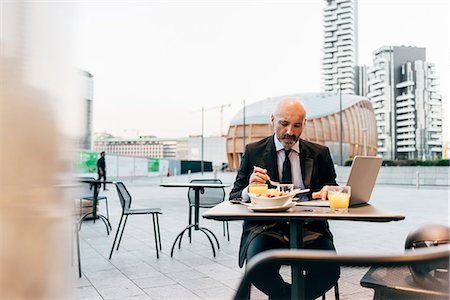 simsearch:649-09061360,k - Mature businessman sitting outdoors at cafe, using laptop Photographie de stock - Premium Libres de Droits, Code: 649-09061353