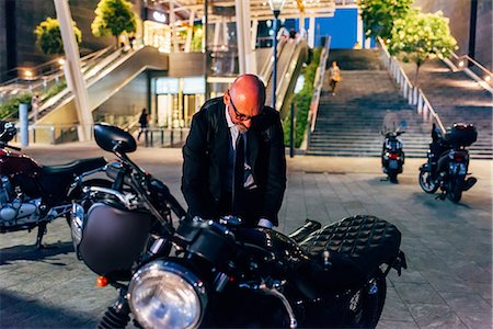 simsearch:649-09061360,k - Mature businessman outdoors at night, preparing to ride motorcycle Photographie de stock - Premium Libres de Droits, Code: 649-09061364