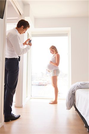 simsearch:649-09061407,k - Man taking smartphone photograph of pregnant girlfriend in bedroom Photographie de stock - Premium Libres de Droits, Code: 649-09061405